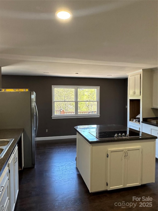 kitchen featuring sink, white cabinets, stainless steel refrigerator, a kitchen island, and dark hardwood / wood-style flooring