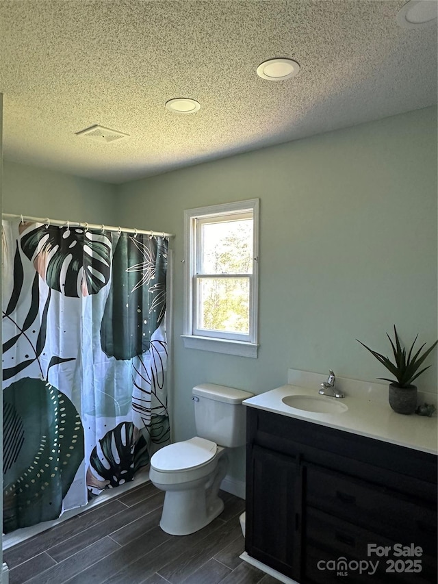 bathroom with toilet, wood-type flooring, vanity, and a textured ceiling