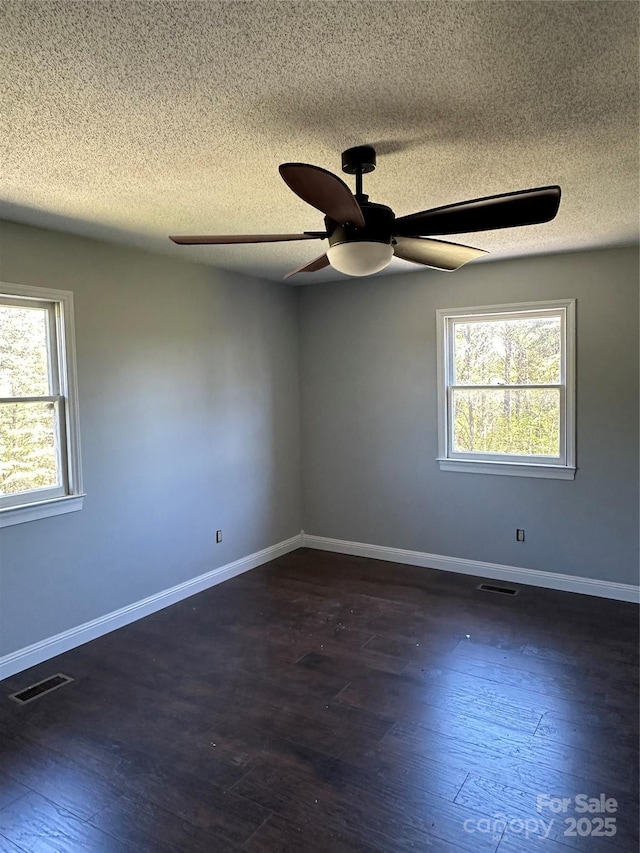 spare room featuring a textured ceiling, ceiling fan, plenty of natural light, and dark hardwood / wood-style floors