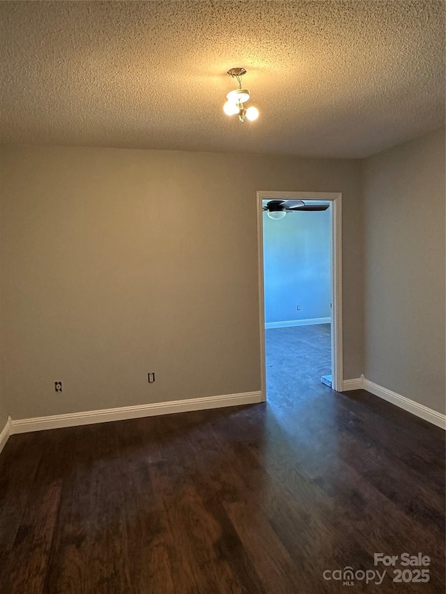 empty room with a textured ceiling and dark hardwood / wood-style floors