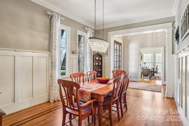 dining room featuring ornate columns, a wealth of natural light, hardwood / wood-style floors, and a notable chandelier