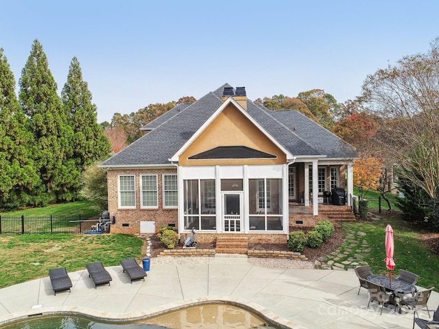 back of property featuring a yard, a patio, and a sunroom