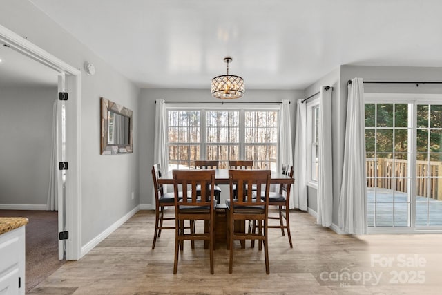 dining space featuring light wood-type flooring and an inviting chandelier