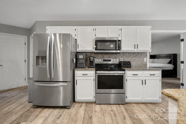 kitchen with white cabinets, appliances with stainless steel finishes, decorative backsplash, light hardwood / wood-style floors, and light stone counters