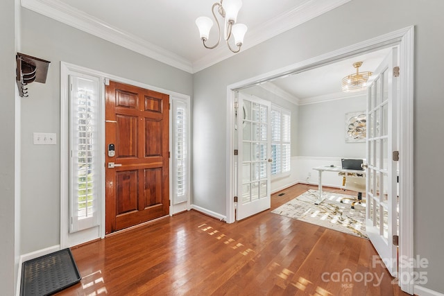 entryway with french doors, hardwood / wood-style floors, crown molding, and a notable chandelier