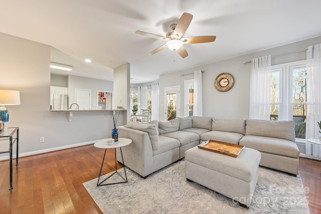 living room featuring vaulted ceiling, ceiling fan, light hardwood / wood-style flooring, and a wealth of natural light