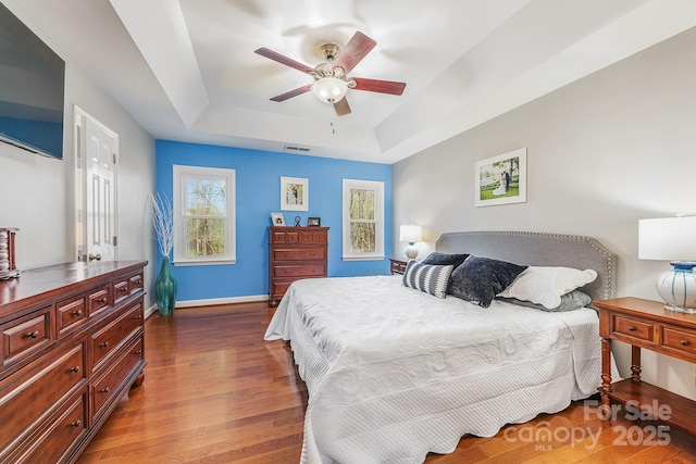 bedroom with a raised ceiling, ceiling fan, and hardwood / wood-style flooring