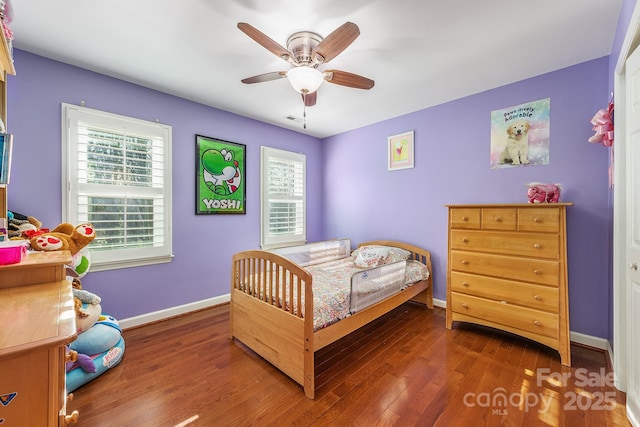 bedroom featuring ceiling fan, multiple windows, and dark hardwood / wood-style floors