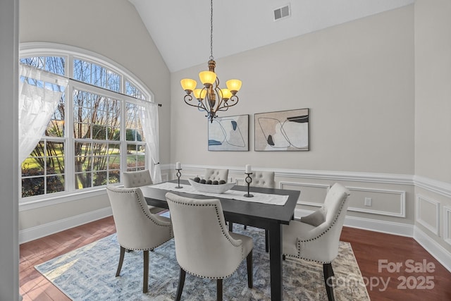 dining area with lofted ceiling, dark wood-type flooring, and a chandelier