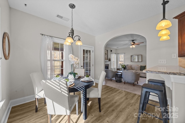 dining room with ceiling fan, a textured ceiling, and light wood-type flooring