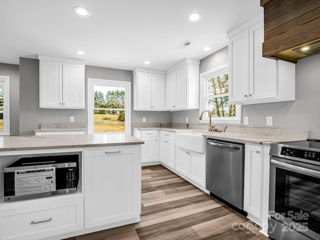 kitchen featuring white cabinets, stainless steel appliances, custom range hood, and light stone countertops