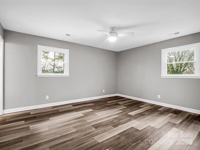 spare room featuring ceiling fan, wood-type flooring, and a healthy amount of sunlight