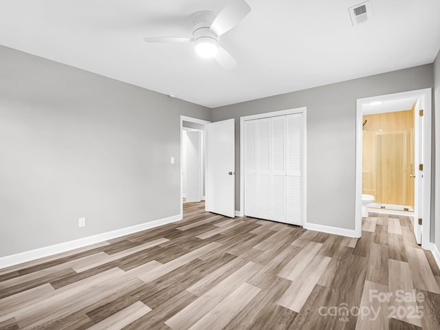 unfurnished bedroom featuring a closet, ceiling fan, ensuite bathroom, and light wood-type flooring