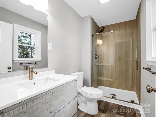 bathroom with wood-type flooring, toilet, walk in shower, and vanity