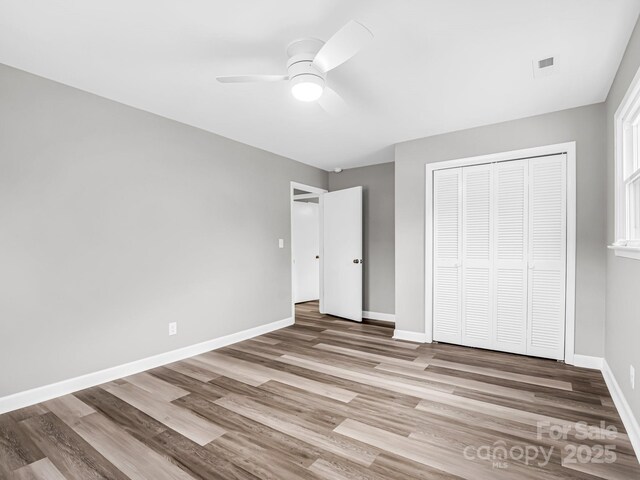 unfurnished bedroom featuring light hardwood / wood-style flooring, a closet, and ceiling fan