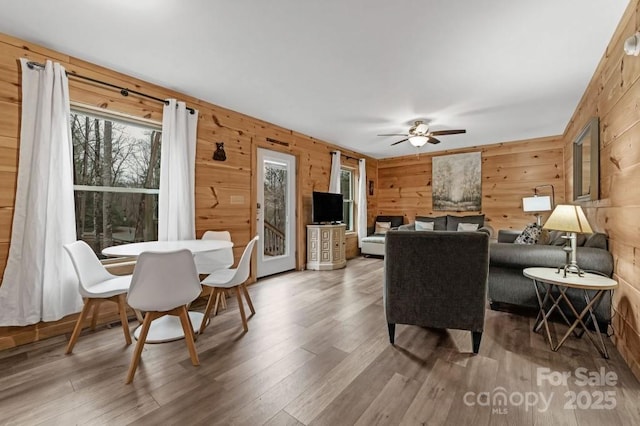 living room with ceiling fan, wooden walls, and hardwood / wood-style floors