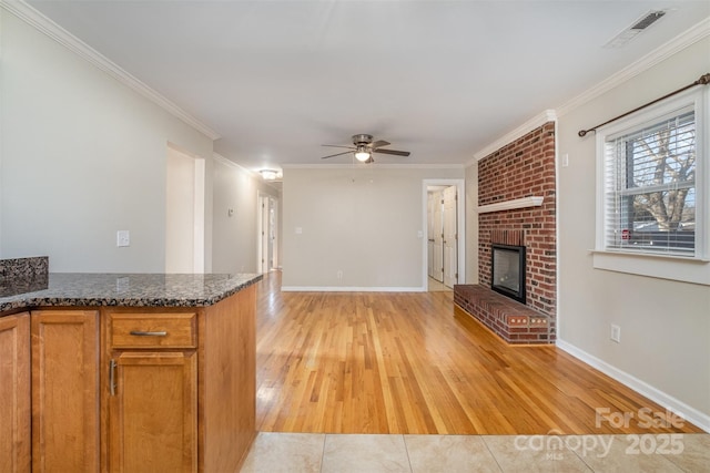 interior space with ceiling fan, light wood-type flooring, ornamental molding, and a fireplace