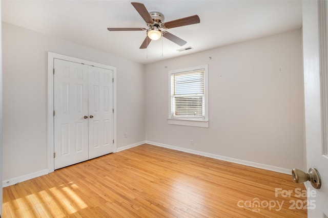 unfurnished bedroom with ceiling fan, a closet, and wood-type flooring