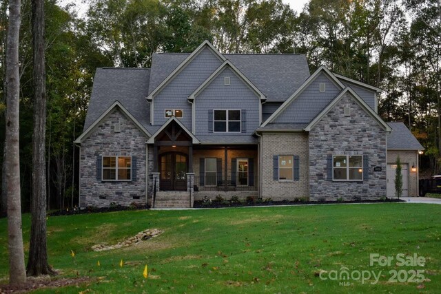 craftsman-style home featuring a front yard, covered porch, and stone siding