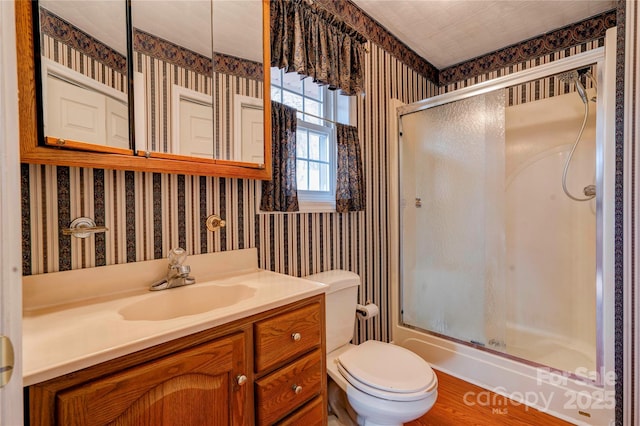 bathroom with toilet, a shower with door, and vanity