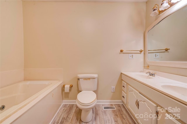 bathroom featuring hardwood / wood-style flooring, toilet, vanity, and a bathing tub