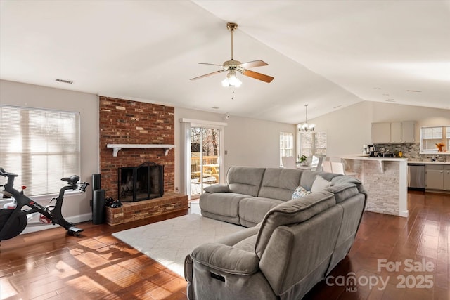 living room featuring ceiling fan with notable chandelier, a wealth of natural light, a fireplace, and dark hardwood / wood-style flooring