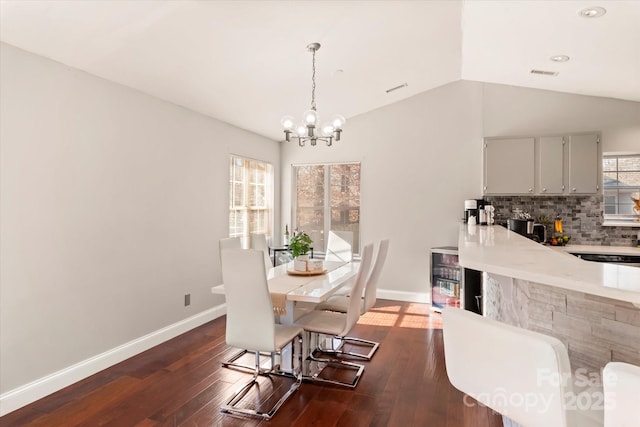 dining room with beverage cooler, dark hardwood / wood-style flooring, a notable chandelier, and vaulted ceiling