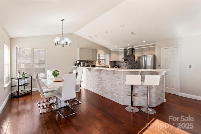 dining space with vaulted ceiling, dark hardwood / wood-style floors, and an inviting chandelier