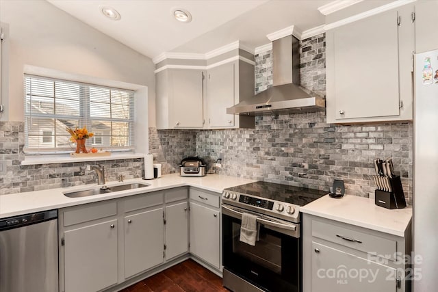 kitchen with gray cabinets, appliances with stainless steel finishes, vaulted ceiling, wall chimney exhaust hood, and sink