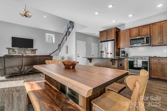 kitchen featuring a center island, stainless steel appliances, decorative backsplash, a kitchen breakfast bar, and light hardwood / wood-style floors