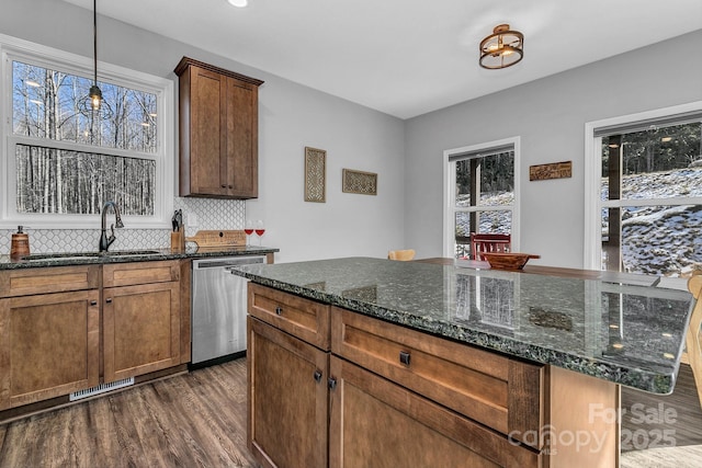 kitchen featuring backsplash, dishwasher, dark stone countertops, a kitchen island, and sink