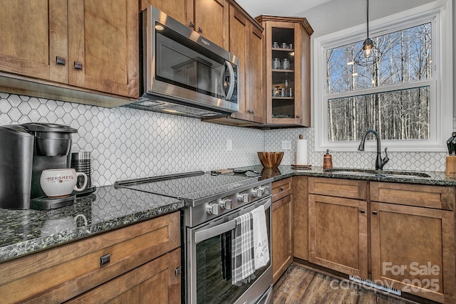 kitchen with sink, pendant lighting, appliances with stainless steel finishes, and dark stone counters