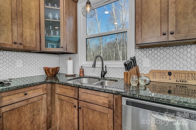 kitchen featuring sink, stainless steel dishwasher, dark stone counters, and tasteful backsplash