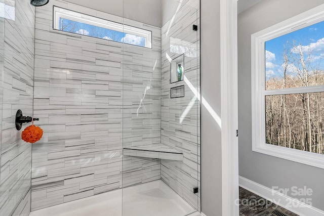 bathroom featuring a shower with door and a healthy amount of sunlight