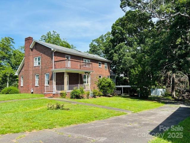 266 Hudlow Rd, Forest City, NC 28043 - view of front of home featuring a balcony, a chimney, a front lawn, and brick siding