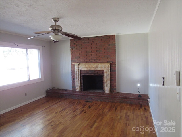 unfurnished living room with a textured ceiling, wood-type flooring, a fireplace, ornamental molding, and ceiling fan