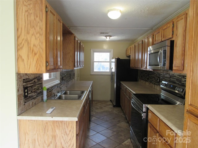 kitchen featuring sink, stainless steel appliances, tasteful backsplash, a textured ceiling, and tile patterned floors