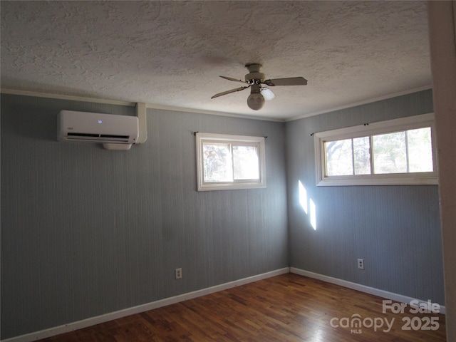 spare room featuring wood-type flooring, a wall unit AC, ceiling fan, crown molding, and a textured ceiling