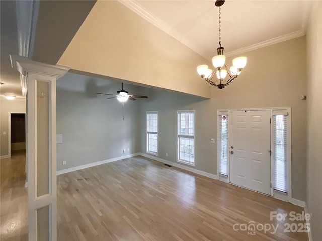 foyer featuring ceiling fan with notable chandelier, wood-type flooring, high vaulted ceiling, and crown molding