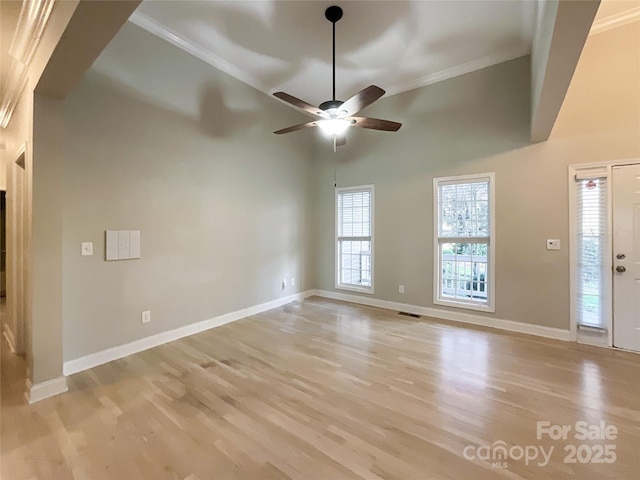 unfurnished living room featuring ceiling fan, crown molding, a towering ceiling, and light hardwood / wood-style flooring