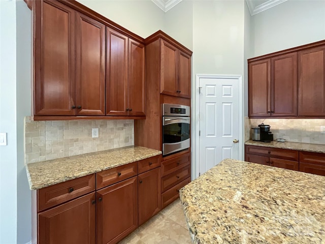 kitchen with crown molding, backsplash, light stone counters, and oven