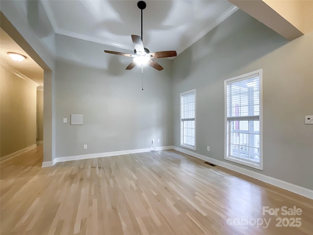 unfurnished room with ceiling fan, crown molding, a towering ceiling, and light wood-type flooring