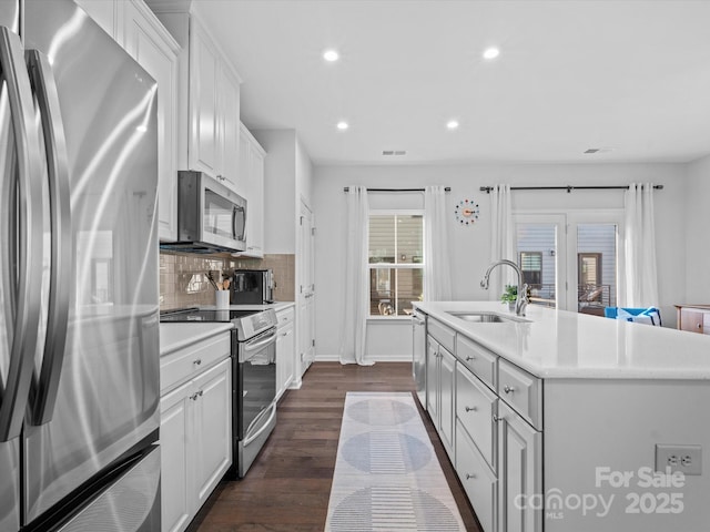 kitchen featuring white cabinetry, stainless steel appliances, tasteful backsplash, sink, and a kitchen island with sink