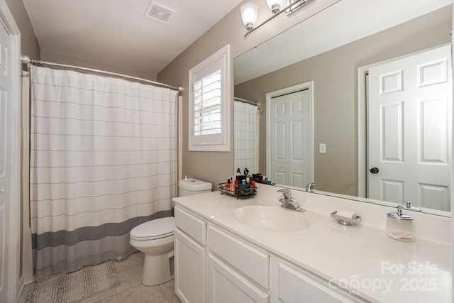 bathroom with toilet, vanity, and tile patterned flooring