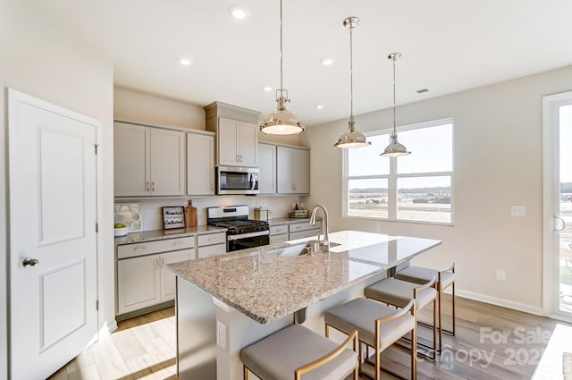 kitchen featuring gray cabinets, appliances with stainless steel finishes, pendant lighting, light stone counters, and sink