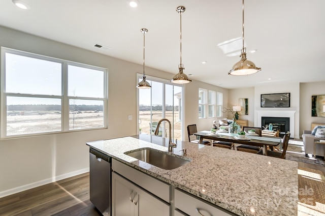 kitchen featuring dishwasher, pendant lighting, dark hardwood / wood-style flooring, light stone counters, and sink