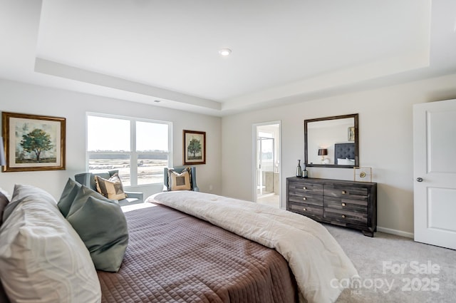 carpeted bedroom featuring ensuite bath and a tray ceiling