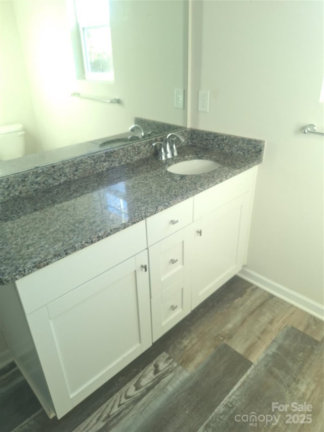 bathroom with toilet, hardwood / wood-style flooring, and vanity