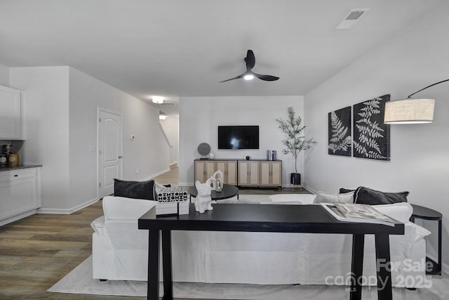 living room featuring dark wood-type flooring and ceiling fan