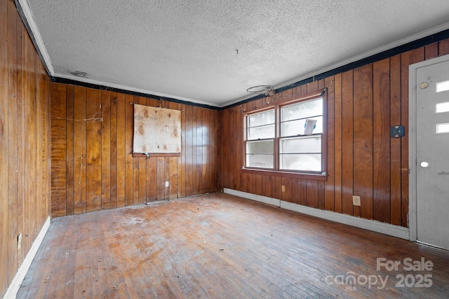 entrance foyer featuring wood walls, hardwood / wood-style floors, ornamental molding, and a textured ceiling